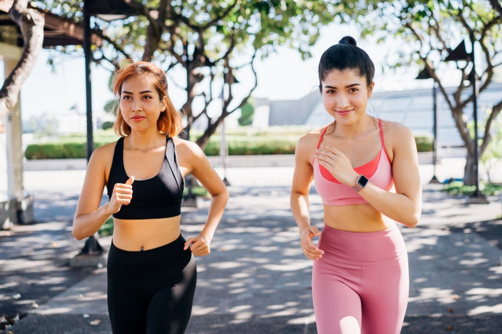 female friends in sports bra running and jogging in outdoor park